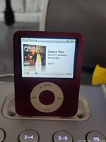 Front view of red Apple iPod Nano 3rd Gen playing music on iHome dock, showing screen and click wheel