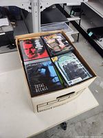 Open bankers box showing DVDs including Total Recall and other titles