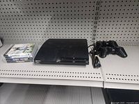 PlayStation 3 Slim console, four game cases, one controller visible