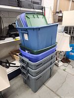Stack of six plastic totes showing three gray Rubbermaid Brute bins on bottom and three lighter-duty totes on top