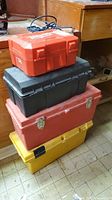 Stack of four toolboxes; yellow toolbox with black latches at bottom is the lot container