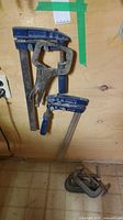 Wall-hung view showing two F-style bar clamps, locking plier clamp, and two C-clamps on floor