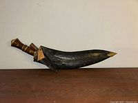 Kukri fully sheathed showing curved profile and brass fittings