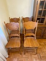 Four of the six oak press-back chairs front view