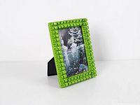 Oblique front view of green ceramic photo frame showing color, pattern and easel stand