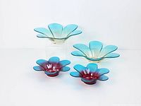 Group shot of four flower-shaped carnival glass votive holders showing two large aqua and two small ruby-aqua pieces