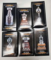 Front view of six sealed boxes showing each trophy design