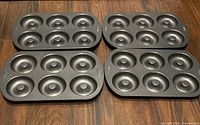 Four identical Wilton 6-cavity donut pans on floor
