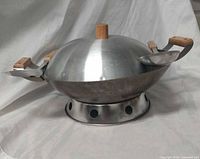 Wok on ring with domed lid and utensils handles visible