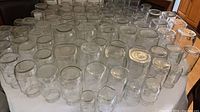 Top view showing large quantity of assorted clear glass canning jars arranged on table
