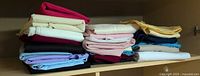 Two stacks of folded solid-colour fabric pieces on shelf
