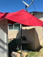 Full view of red patio umbrella erected beside shed
