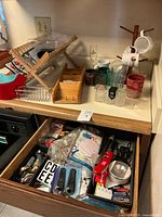 Overview of countertop and open drawer showing wooden dish rack, mail/key rack, drinkware, spice jars, metal rack, clear tray, drawer items