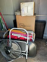 Overall lot showing dog crate, Mainstays box, beach chairs, fan, ladder