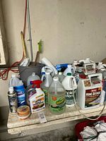 Wide view of countertop with multiple gallon jugs, spray bottle, Flex Seal can, wax tubs, and bucket