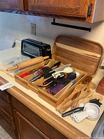 Overall lot with bamboo organizer filled with utensils, rolling pin, bamboo utensils, measuring cups and cutting board
