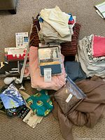 Overview of linens, packaged sheet sets, brown bedding bag, bulbs, rod and showerhead