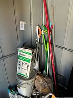 Corner of shed with mops, broom, rake, shovel, paint bucket, and Chapin sprayer box