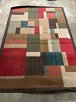 Full view of multicolor geometric rug showing pattern and dark brown border
