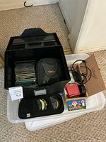 Entire lot: black storage box with CDs, disc wallets, GBA SP console, charger, headphones visible