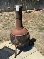 Full view of rusted cast iron mesh chiminea on patio