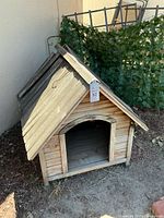 Front and side view of wooden dog house showing arched entry and weathered wood
