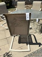 Rear view of one beige metal cantilever chair showing tan sling fabric and size tag