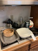 Wide view of lot on stovetop including appliances, electric skillet, glass dish, wooden bowl, cast iron pan