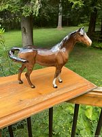 Full left-side view of brown glazed horse figurine on railing