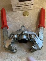 Front view of BREV handheld bottle capper with loose cap and box visible