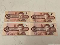 Four Canadian $2 notes laid out on countertop
