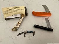All four pocket knives displayed on surface with box