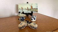 Group shot showing all Delft items: mortar ashtray with pestle, clog ashtray, pair of clogs, scenic tile on stand