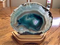 Front view of polished agate geode slice on stand showing banding and druzy cavity