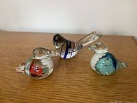 Group shot of three clear glass bird figurines displaying size and design differences