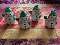 Front view of four ceramic snowman ornaments