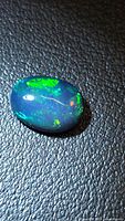 Front view of oval black opal showing green and red play-of-color