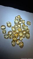 Group of translucent yellow oval and pear citrine cabochons on white background