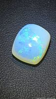 Cushion cabochon opal on dark background showing multicolor play-of-color
