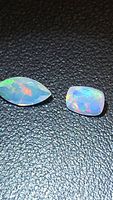 Marquise and cushion opal pair on black background showcasing play of color