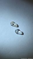 Two pear-cut colorless zircons on white surface