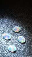 Four oval faceted opals on dark background