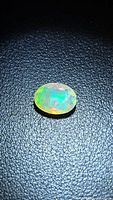 Front view of oval faceted opal displaying multicolour fire