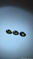 Three oval faceted sapphires on light background showing colour zoning