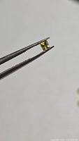 Square-cut yellow sapphire held in tweezers