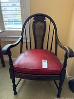 Full view of wooden armchair with cane back and red vinyl seat