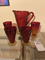 Pitcher and four goblets displayed on glass surface