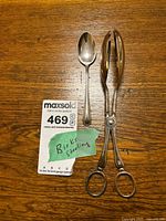 Spoon and tongs laid on wood surface with tag visible