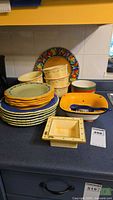 Group shot of all stacked plates, bowls, square dishes and ladle