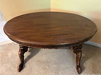 Front view of oval wood coffee table showing legs and stretcher